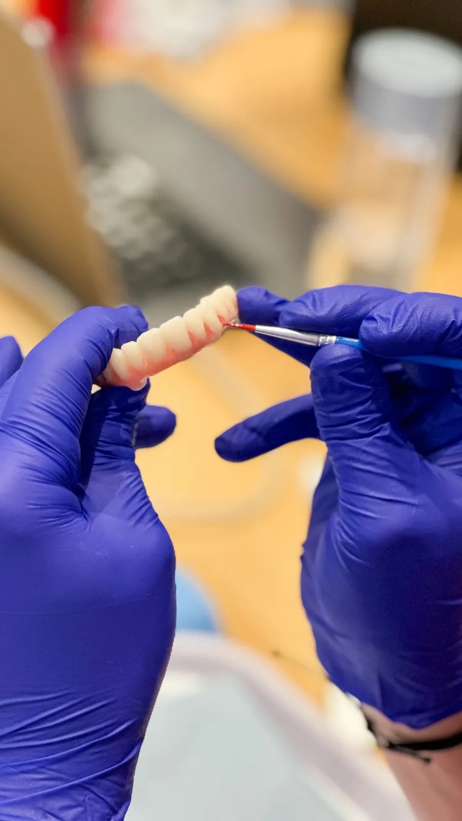 A technician finishing a printed full-arch prosthesis by hand at the bench